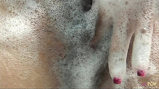 Playful cutie takes a soapy bath and fingers her hairy pussy