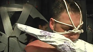 BDSM mistress in thigh-highs ropes dude's collared face and pulls his bound cock